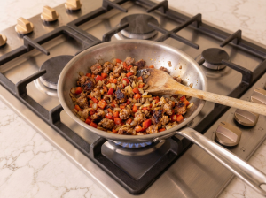 Cooking the onion, sausage meat and other ingredients in a stainless steel pan