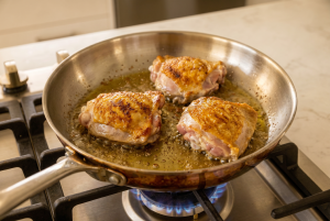chicken thighs cooking in a saucepan