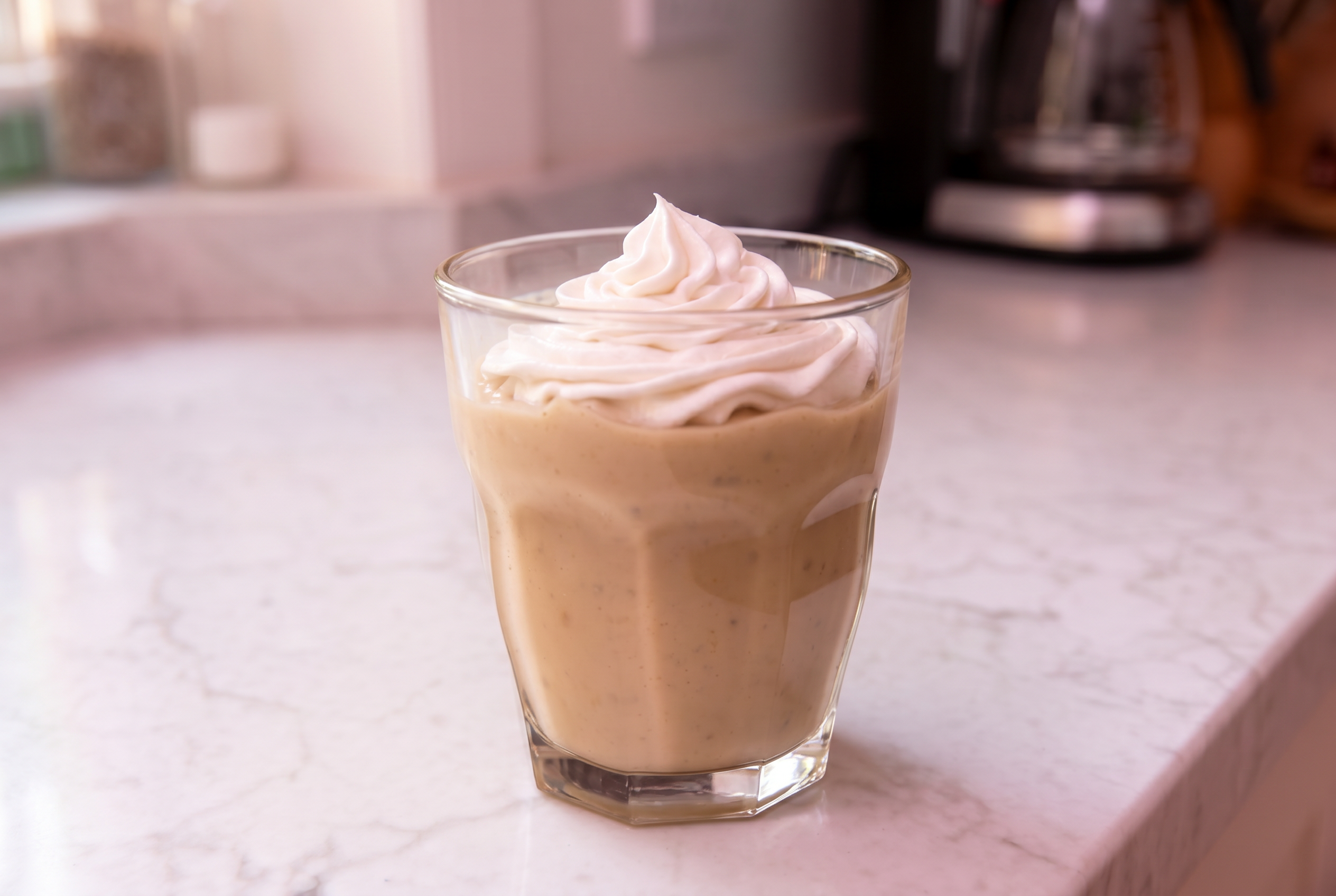 keto white tea in a glass cup with swirly whipped cream on top